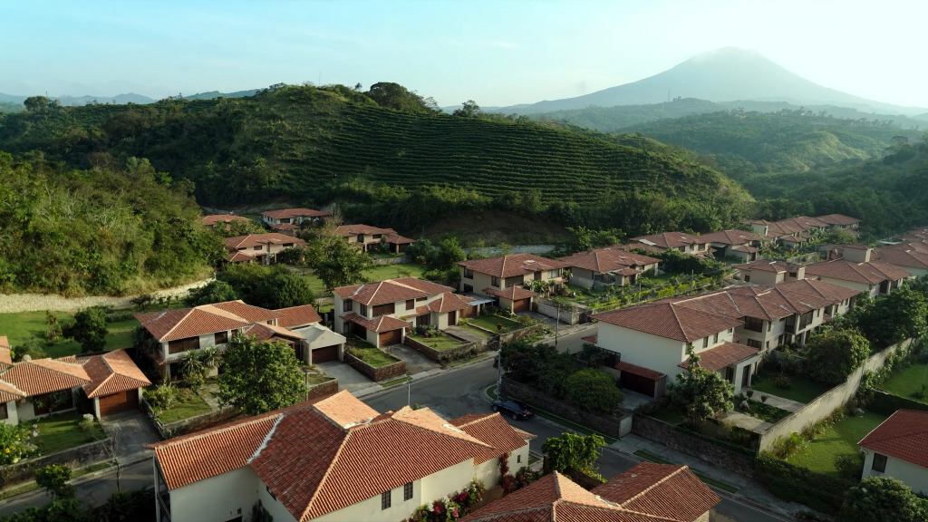 Vista aérea de un residencial en el Valle Central de Costa Rica, viviendas con techo de teja y cafetales al fondo